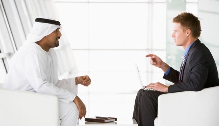 A Middle Eastern man and a caucasian man talking at a business m